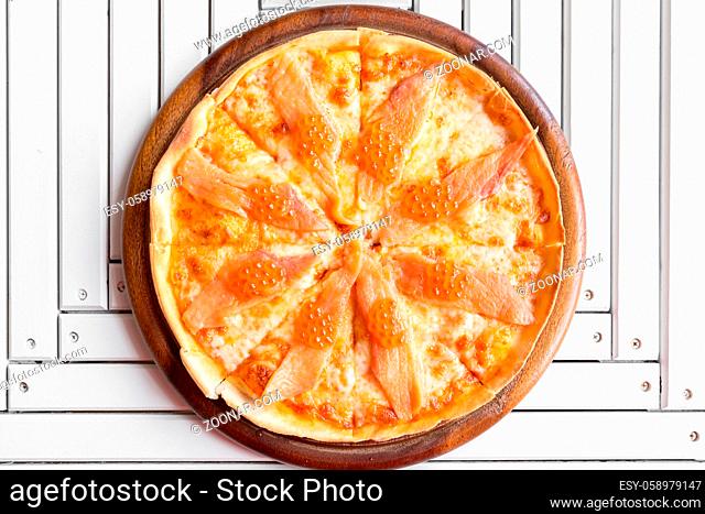 Pizza with smoked salmon and egg on white wooden table