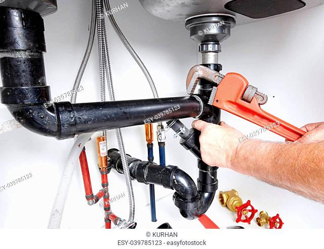 Hands of professional Plumber with a wrench. Clogged sink