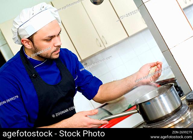 professional chef cook adding rice in pot for boiling soup in commercial kitchen