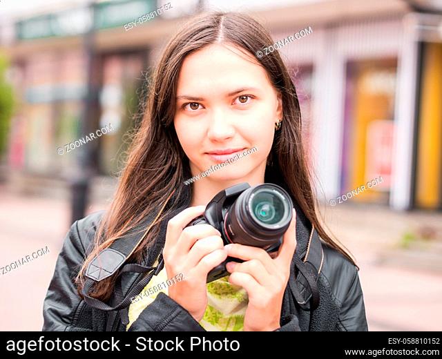 Woman on vacation photographing with dslr camera on city street. Looking at camera. Vacation photography travel concept