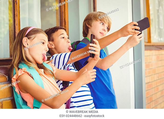 School kids taking selfie with mobile phone in corridor