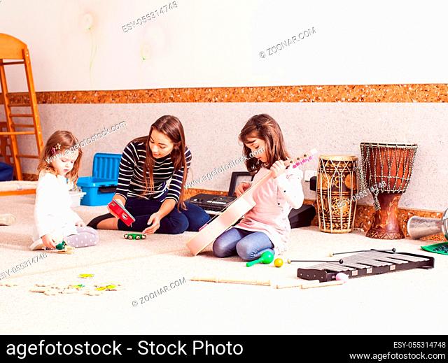 Music making lesson. The young woman teacher plays with children, little orchestra