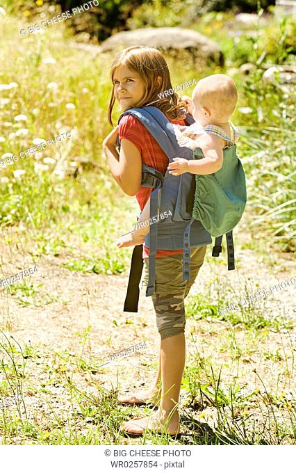 Girl carrying baby sibling on back