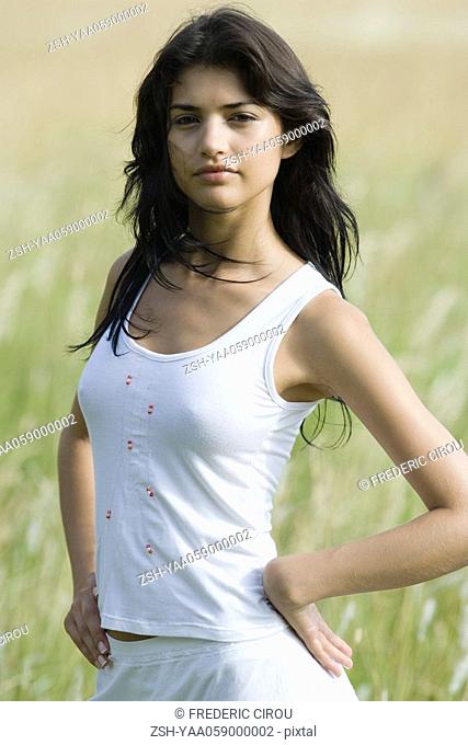 Young woman standing in field, looking at camera, portrait