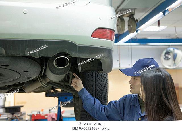 Mechanic pointing at the bottom of a car