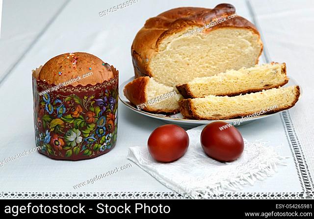 On the table on a white napkin are two painted Easter eggs, next on the plate of sliced cake