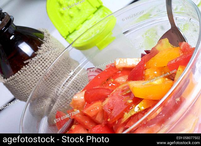 Vegetables: tomatoes, onions are sliced for salad and placed in a glass container. Nearby is a bottle of vegetable oil and salt shaker