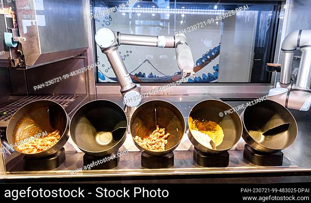 PRODUCTION - 20 July 2023, Schleswig-Holstein, Grömitz: A robot prepares dishes in induction trays in a hotel restaurant