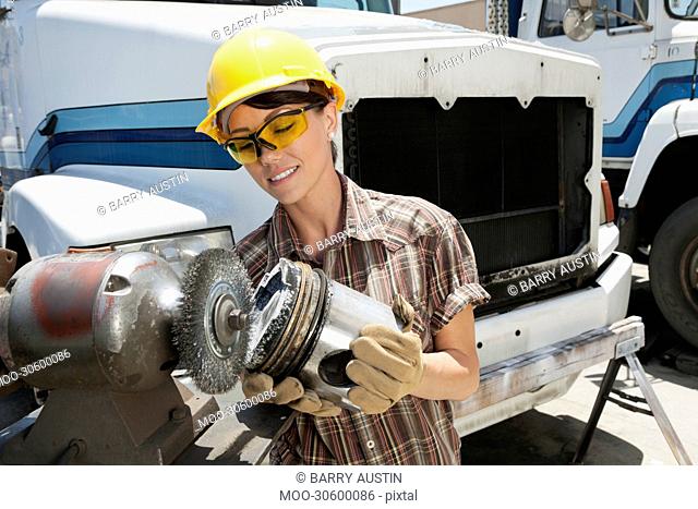 Female industrial worker buffing a truck engine cylinder