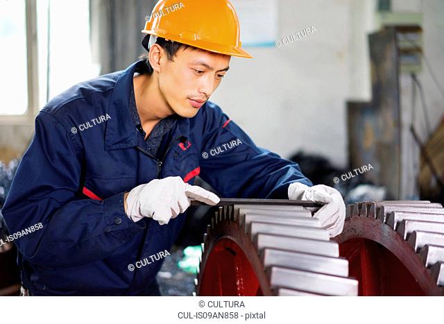 Worker using equipment in crane manufacturing facility, China