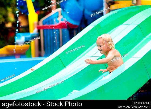 Kids play in aqua park. Children at water playground of tropical amusement park. Little boy at swimming pool. Child playing at water slide on summer vacation in...