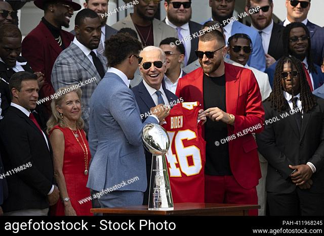 Kansas City Chiefs quarterback Patrick Mahomes (light blue suit) and tight end Travis Kelce (red suit) present United States President Joe Biden with a team...