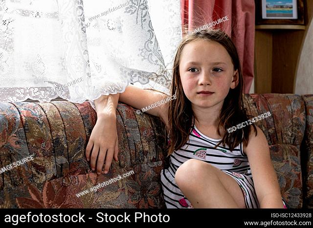 Portrait of girl (4-5) sitting on sofa in caravan
