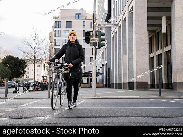 Woman with bicycle in the city on the go, Frankfurt, Germany