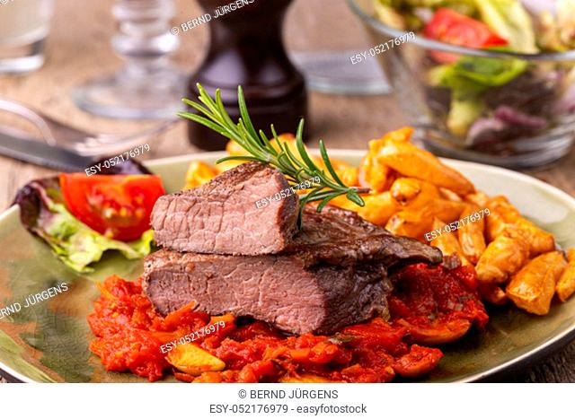 grilled steak on a plate with rosemary