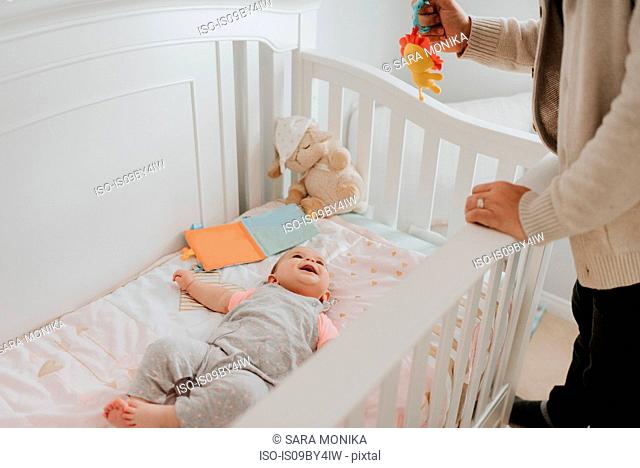 Father putting baby daughter to bed in crib