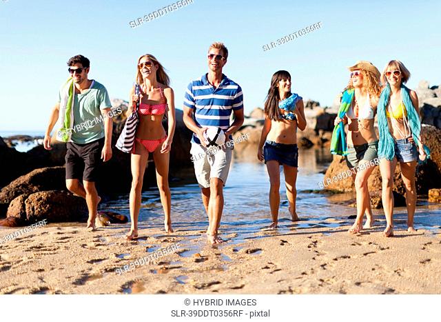 Smiling friends walking on beach