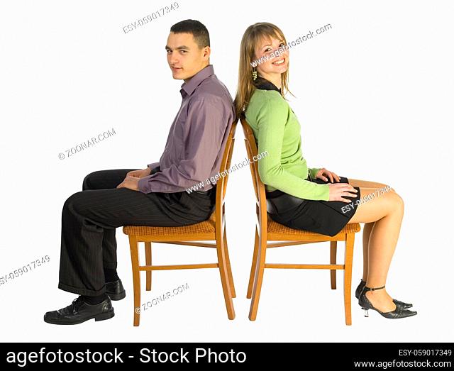 Man and woman sitting on the chairs back to eachother. Isolated on white in studio