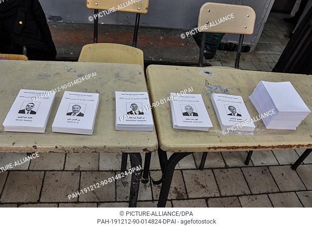 12 December 2019, Algeria, Algiers: Ballots with pictures of the five Algerian presidential candidates lie on a desk inside a polling station during the first...
