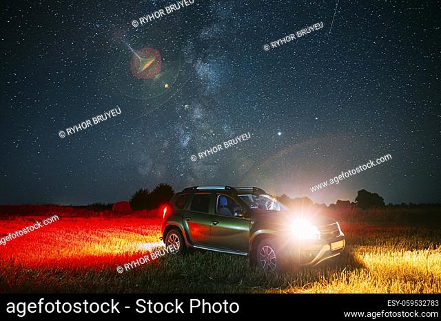 Night Starry Sky With Glowing Stars Above Car SUV In Countryside Landscape. Milky Way Galaxy And Rural Field Meadow