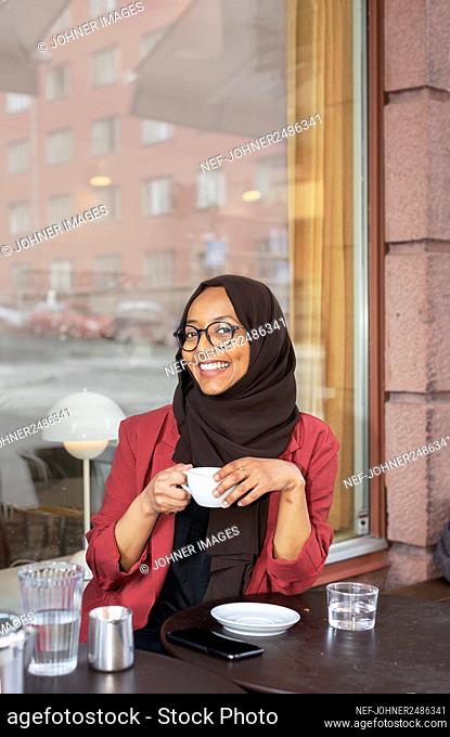 Smiling woman having coffee in outdoor cafe