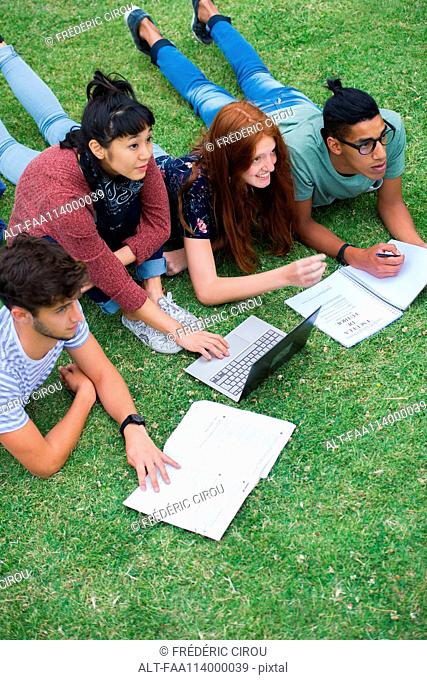 Group of college students lying on grass studying