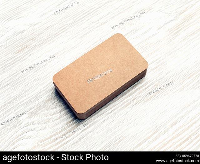 Blank kraft business cards stack on light wooden background. Corporate identity template