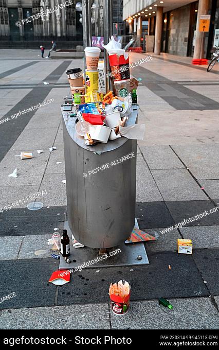 11 March 2023, North Rhine-Westphalia, Cologne: A full public trash can, trash cans overflowing with disposable packaging, coffee cups, etc