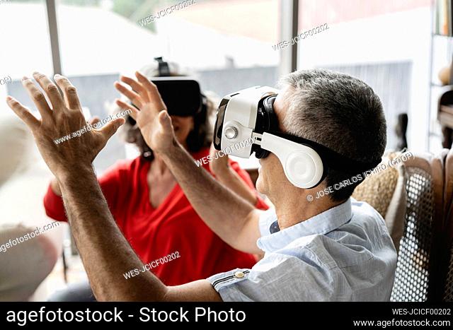 Business colleagues wearing virtual reality simulator gesturing in workplace
