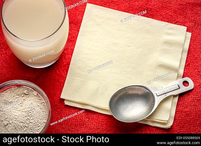 food grade diatomaceous earth supplement - powder and in a glass of water with a measuring spoon and a napkin