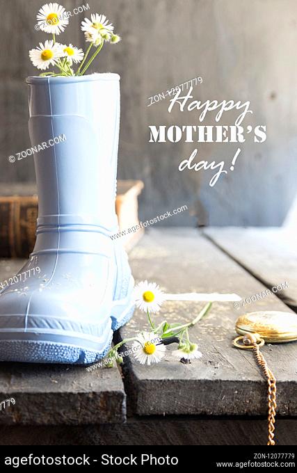 Daisy and boots on a vintage background and text Happy Mothers Day lettering.