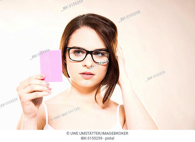 Young woman looking at herself in a cosmetic mirror, Mannheim, Baden-Württemberg, Germany
