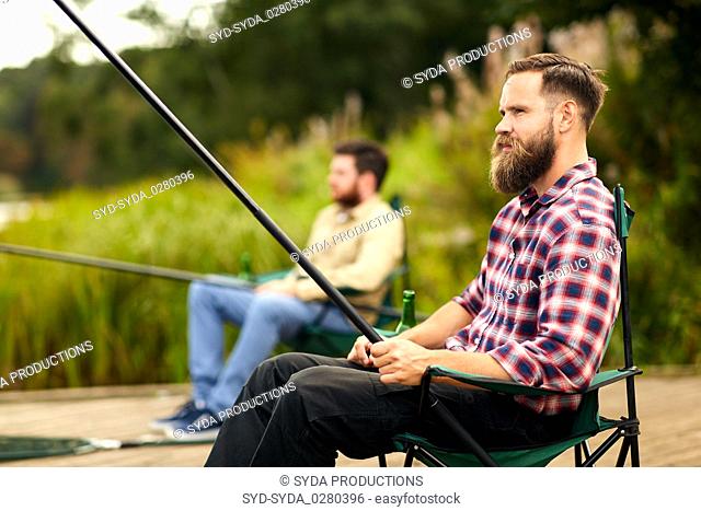 bearded man with friend fishing at lake