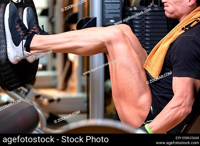 Handsome strong man performed leg press workout in the gym