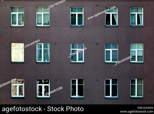 Architectural background of the exterior of an apartment or office block with rows of identical windows, some with curtains