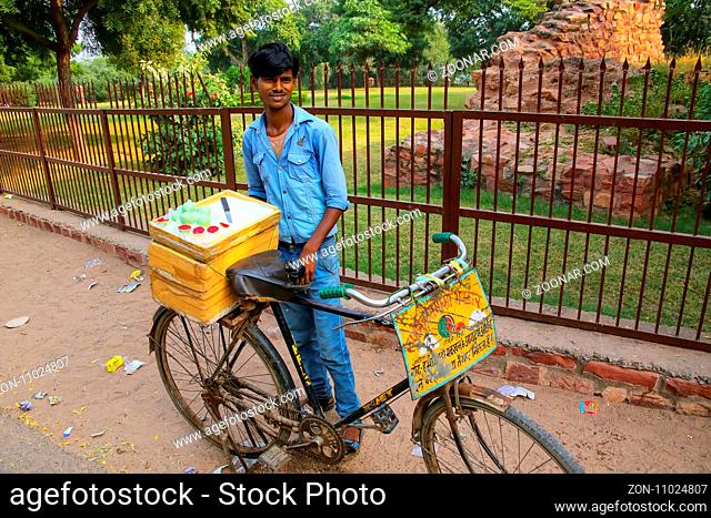 Young man selling desserts from a bicycle outside Jama Masjid in Fatehpur Sikri, Uttar Pradesh, India. The city was founded in 1569 by the Mughal Emperor Akbar