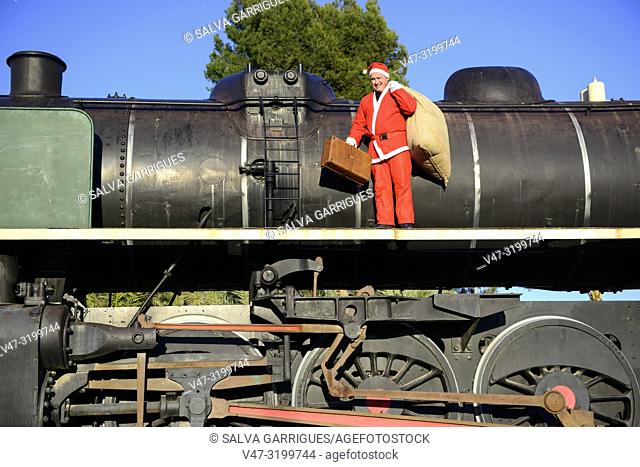 Santa Claus with a suitcase goes on travel trip in a steam train locomotive