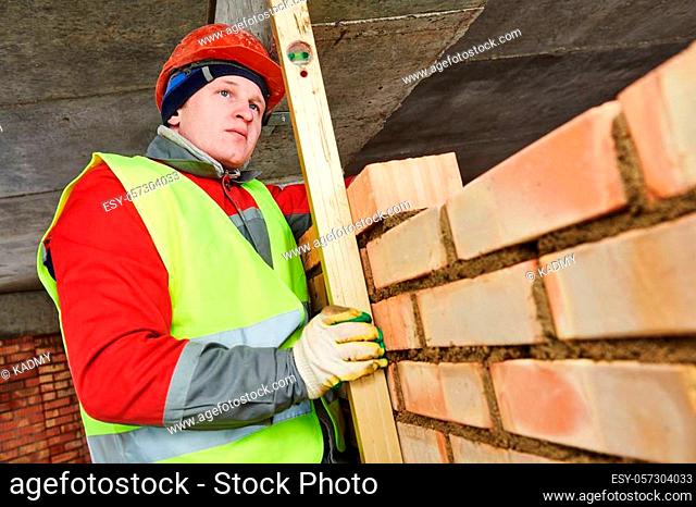 Bricklaying construction work or walling. bricklayer builder working laying bricks. Checkup the level