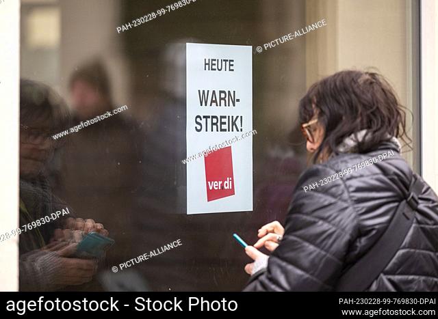 28 February 2023, Baden-Württemberg, Tübingen: A woman stands in front of a window of the public library where a poster with the inscription ""Today warning...