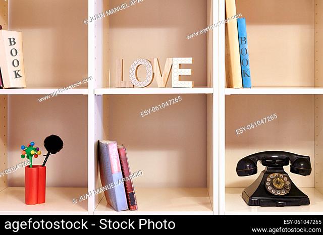 shelf with books old phone and letters with the word love