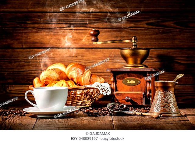 Coffee cup with croissants and coffee beans on wooden background