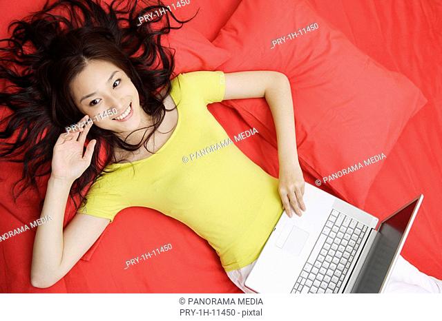 Young woman lying in bed with laptop