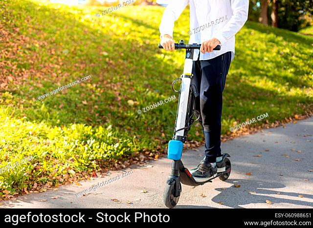 Joyful and casual man riding electric scooter in the city park