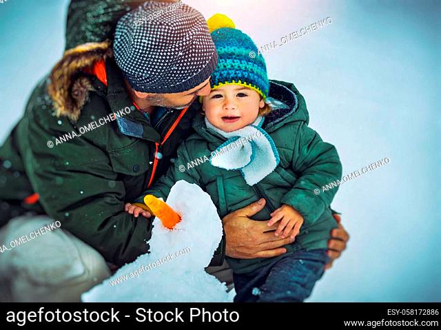 Portrait of a Happy Father with His Cute Little Son Building Snowman Together. Enjoying Winter Time. Happy Christmastime Holidays