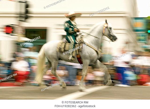 Mexican horseback riders trot along during the opening day parade down State Street of Old Spanish Days Fiesta held every August in Santa Barbara, California
