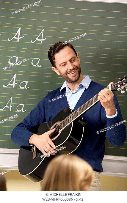 Teacher playing guitar in classroom
