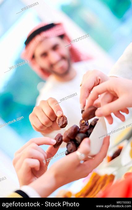 Eid Mubarak Muslim family having Iftar dinner eating dates to break feast. Eating traditional food during Ramadan feasting month at home