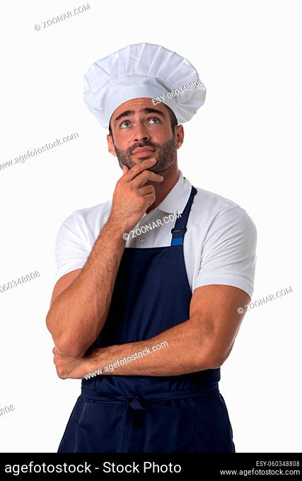 Portrait of male cook in apron and hat thinking holding hand on chin and looking up isolated on white background