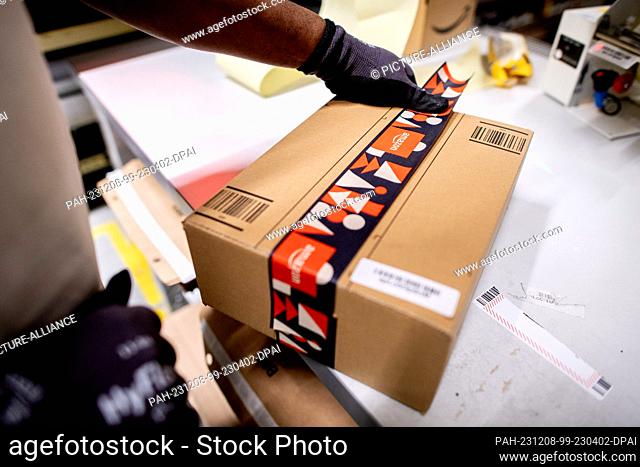 07 December 2023, Lower Saxony, Großenkneten: An outgoing goods employee packs an item for shipping at Amazon's new logistics center at the former Ahlhorn air...