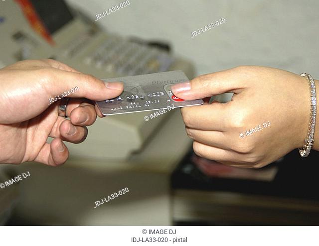 View of two people holding a credit card